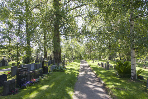 Kalevankankaan hautausmaa kesäpäivänä, puista heijastuvat varjot hiekkatielle, mikä kulkee hautojen vierestä.