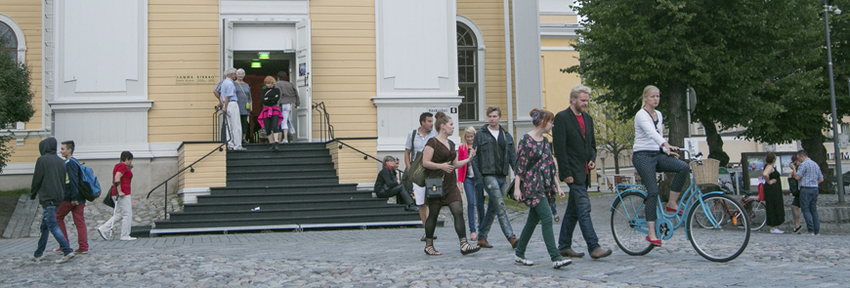 Tampereen keskustorin Vanhan kirkon edustalla on paljon ihmisiä. On lämmin kesäpäivä.