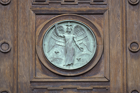 Puisessa ovessa on koristeena ajan patinoima ieni pyöreä veistosenkeli, joka pitää toista kättä ylhäällä.