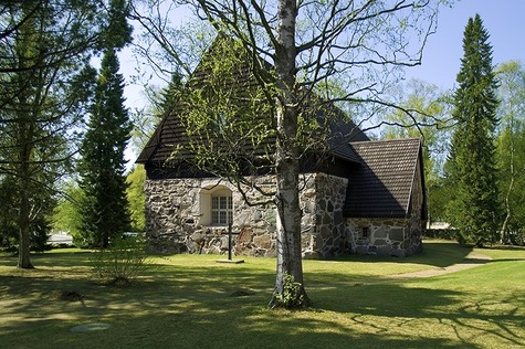 Messukylän vanha kirkko kivikirkkoa ympäröi keväinen luoto ja isot puut.