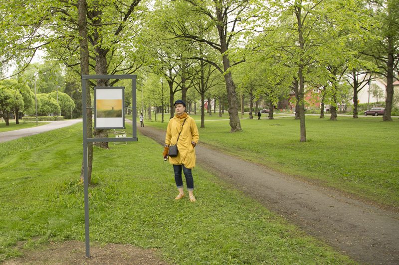 Nainen lukee Viinikan Hiljaisen polun ohjekylttiä, taustalla on vehreä puisto.