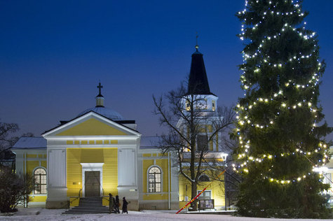 Ihmiset kävelevät kohti Vanhaa kirkkoa jouluna. On hämärä, etualalla on Keskustorin suuri joulukuusi.