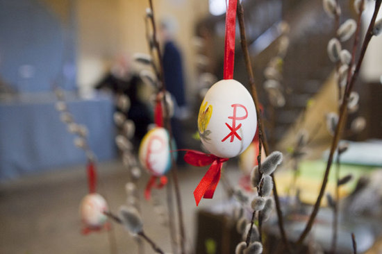 Pajunoksankimppuun on ripustettu panaisella silkkinauhalla valkoisia kananmusnia joissa lukee INRI.