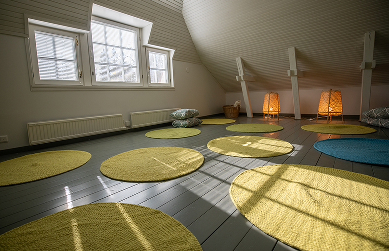 Virkkulan ullakon joogahuoneen maalatulla puulattialla on pyöreitä, keltaisia mattoja.