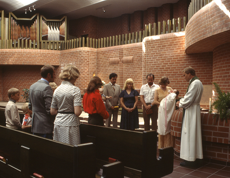 Ihmiset ovat kokoontunet kastettavan lapsen ympärille Hervannan kirkossa.