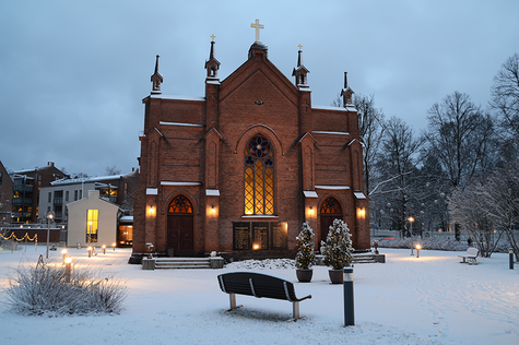 Finlaysonin kirkko kuvattuna ulkona. Maassa on lunta ja jouluvaloja on laitettu kirkon pihamaalle puihin.