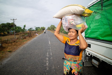 Myanmarilainen nainen kantaa päänsä päällä avustustarvikkeita.