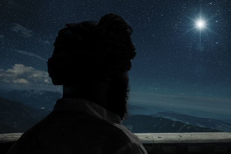 Huivipäinen mies katsoo siniselle taivaalle jossa loistaa iso kirkas tähti.