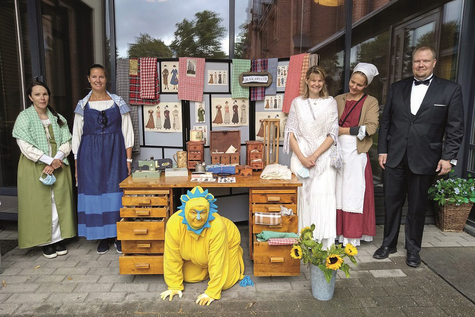 Vanhoihin vaatteisiin pukeutuneita henkilöitä ja leijona-asuinen hahmo poseeraavat.