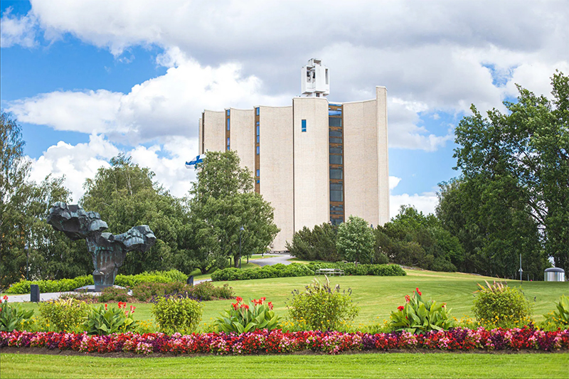 Kalevan kirkon julkisivu. Kirkkoa ympäröi Liisanpiston kesäinen kukkaloisto.