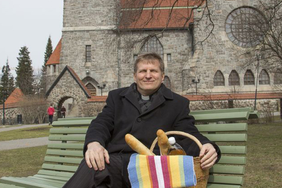 Olli Hallikainen istumassa penkillä Tampereen tuomiokirkon edustalla.