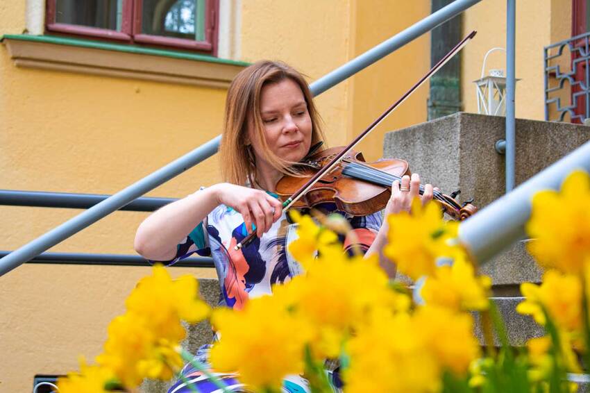 Female instrument instructor plays the violin in the courtyard of the Viinika church.