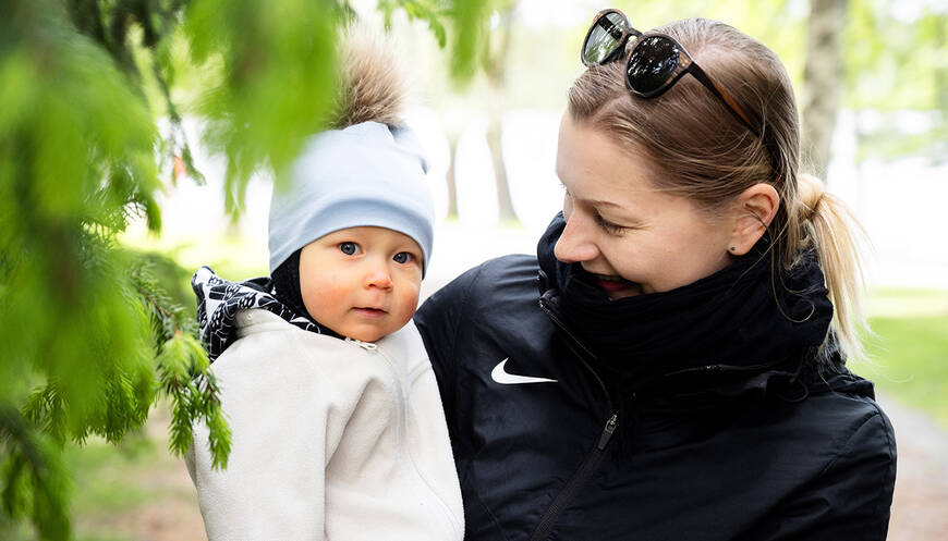 Lapsi hymyilee äitinsä sylissä.