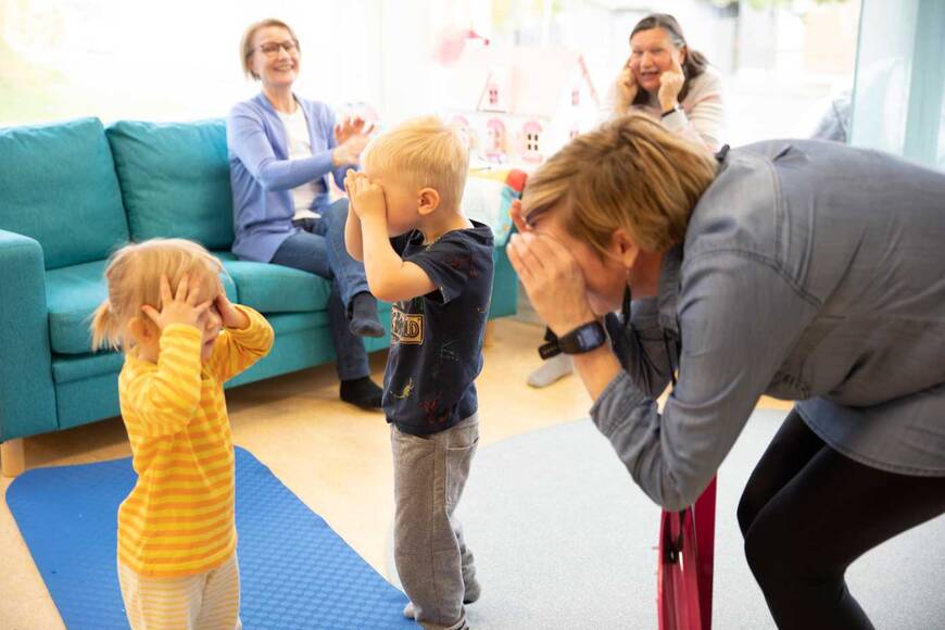 Kaski lasta ja aikuinen leikkivät ja he ovat tehneet käsistään kiikart silmiinsä.