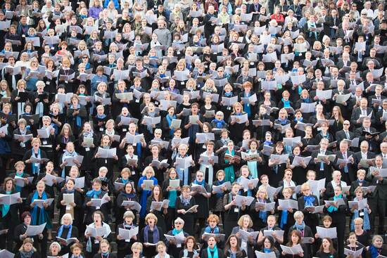 Sadat laulajat pitävät nuotteja käsisään ja laulavat.