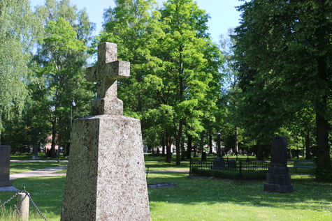 Suuri kivinen hautaristi kirkkopuistossa.