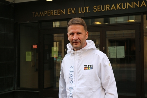 Tuomiorovasti Olli-Pekka Silfverhuth seisoo Tampereen seurakuntien rakennuksen edustalla. Hän on pukeutunut Suomen paralympiajoukkueen edustusasuun.