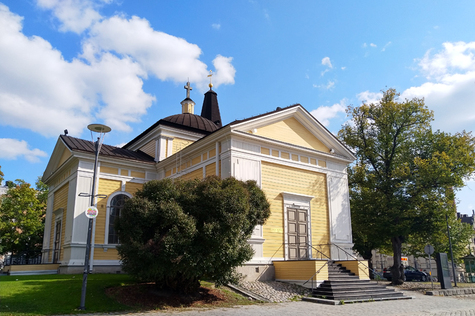 Keltaisella maalattu puukirkko Tampereen Keskustorin laidalla.