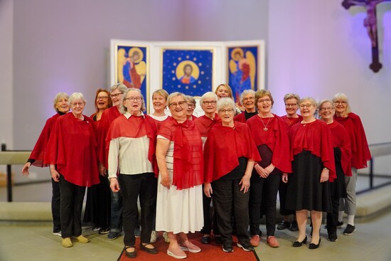 Iloisia naisia seisoo punaisessa viitassa kirkon alttarin edessä.