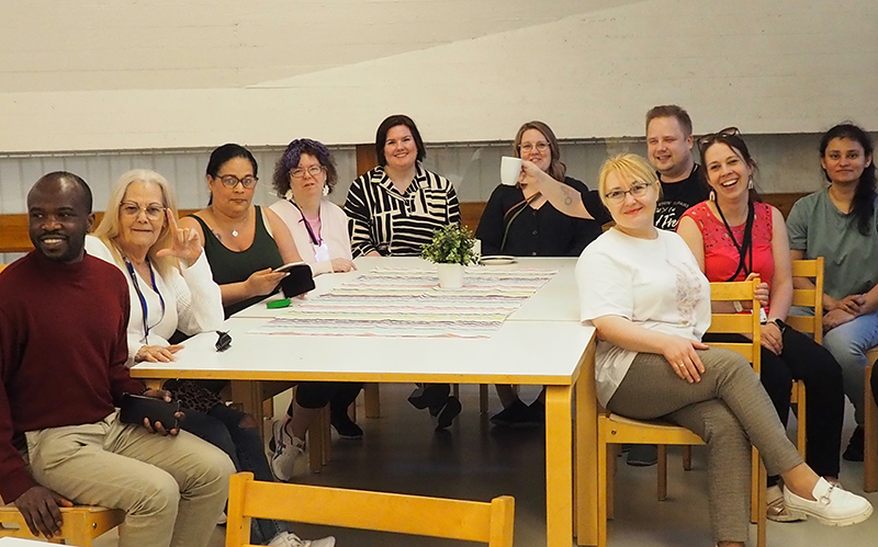 Kymmenen ihmistä istuu pöydän ääressä.