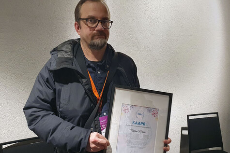 Hymyilevällä miehellä on käsissä kunniakirja, jossa lukee 2025  Kaapo – digitaalisen nuorisotyön innovaatiopalkinto.