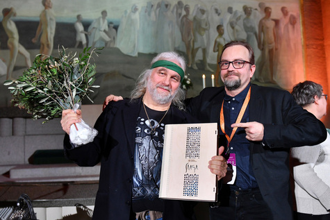 Kaksi miestä Tampereen tuomiokirkon alttarin edustalla, toisella kukkapuska ja kunniakirja kädessä.