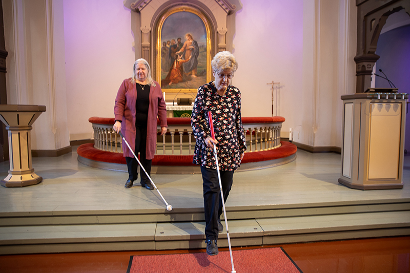 Kaksi naista kävelee keppien kanssa kirkossa alttarin edessä.
