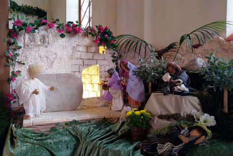 Kerronta-alttarilla nukkeja, joiden avulla kerrotaan pääsiäisen tapahtumista. Nukkehahmoja tyhjän haudan äärellä, haudasta loistaa valo.