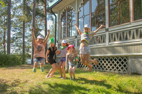 Viisi kymmenenvuotiasta riemuitsee nurmikolla.