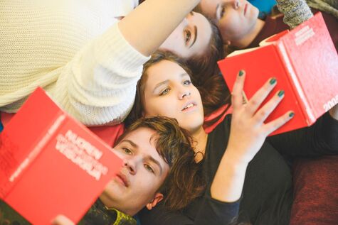 Isoset makaavat lattialla veisukirjat käsissään.