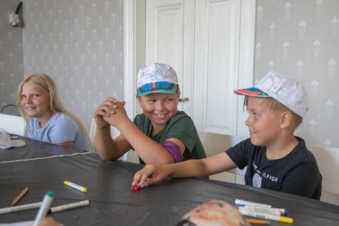 Kolme koululaista istuu pöydän ääressä askartelemassa.