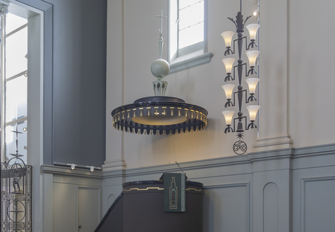 Tumman lieriön muotoisen saarnatuolin päällä on koristeellinen katos.