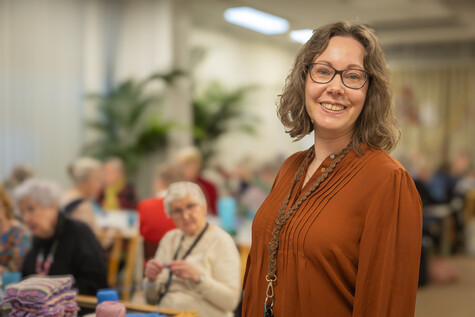 Hymyilevä Maarit Saarela, taustalla Mummon Kammarin peittotalkoisiin osallistuvia.