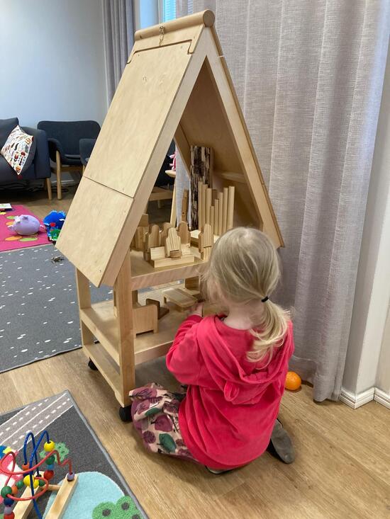 Kuvassa lapsi leikkii puisella nukkekirkolla Pispalan kirkolla.