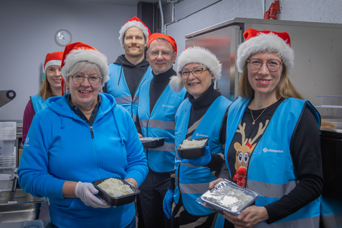 Ruokapankilla puuroa pakkaamassa henkilöitä tonttulakit päässä.