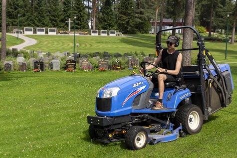 Nuori henkilo ajaa ruohonleikkuria hautausmaalla.