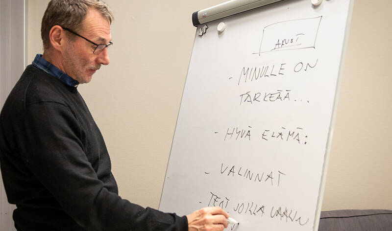 Henkilö kirjoittaa tussilla sanoja muistitauluun.