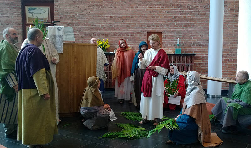 Joukko ihmisiä kaapumaisissa vaatteissa tilassa, jossa on tiiliseinät. Keskellä oleva henkilö selittää jotain.