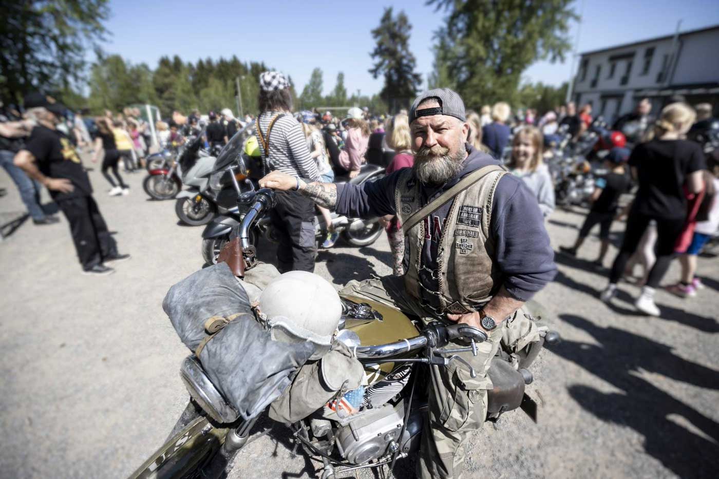 Parrakasmies istuu moottoripyörän selässä.