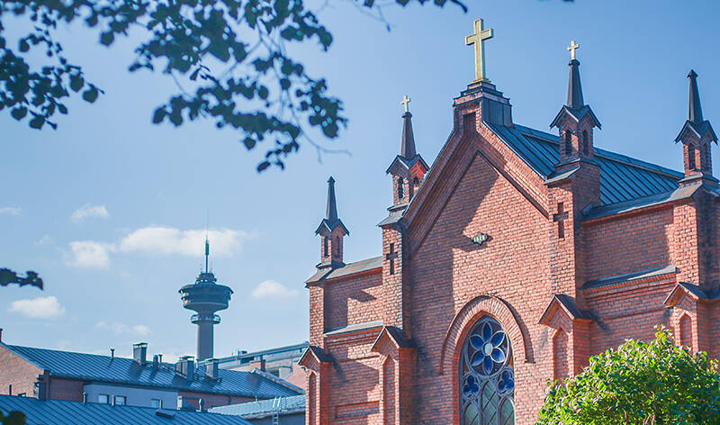 Finlaysonin kirkko kesäisessä auringonpaisteessa edestäpäin kuvattuna. Kuvassa myös Näsinneula ja etualalla puun oksa.