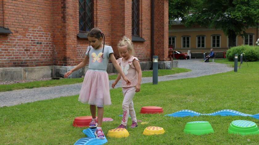 Sela Aleman (vas.) ja Matilda Paloaho leikkivät lasten kesäpihalla Finlaysonin kirkolla.