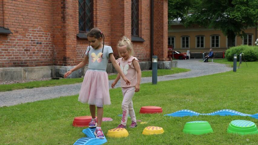 Sela Aleman (vas.) ja Matilda Paloaho leikkivät lasten kesäpihalla Finlaysonin kirkolla.