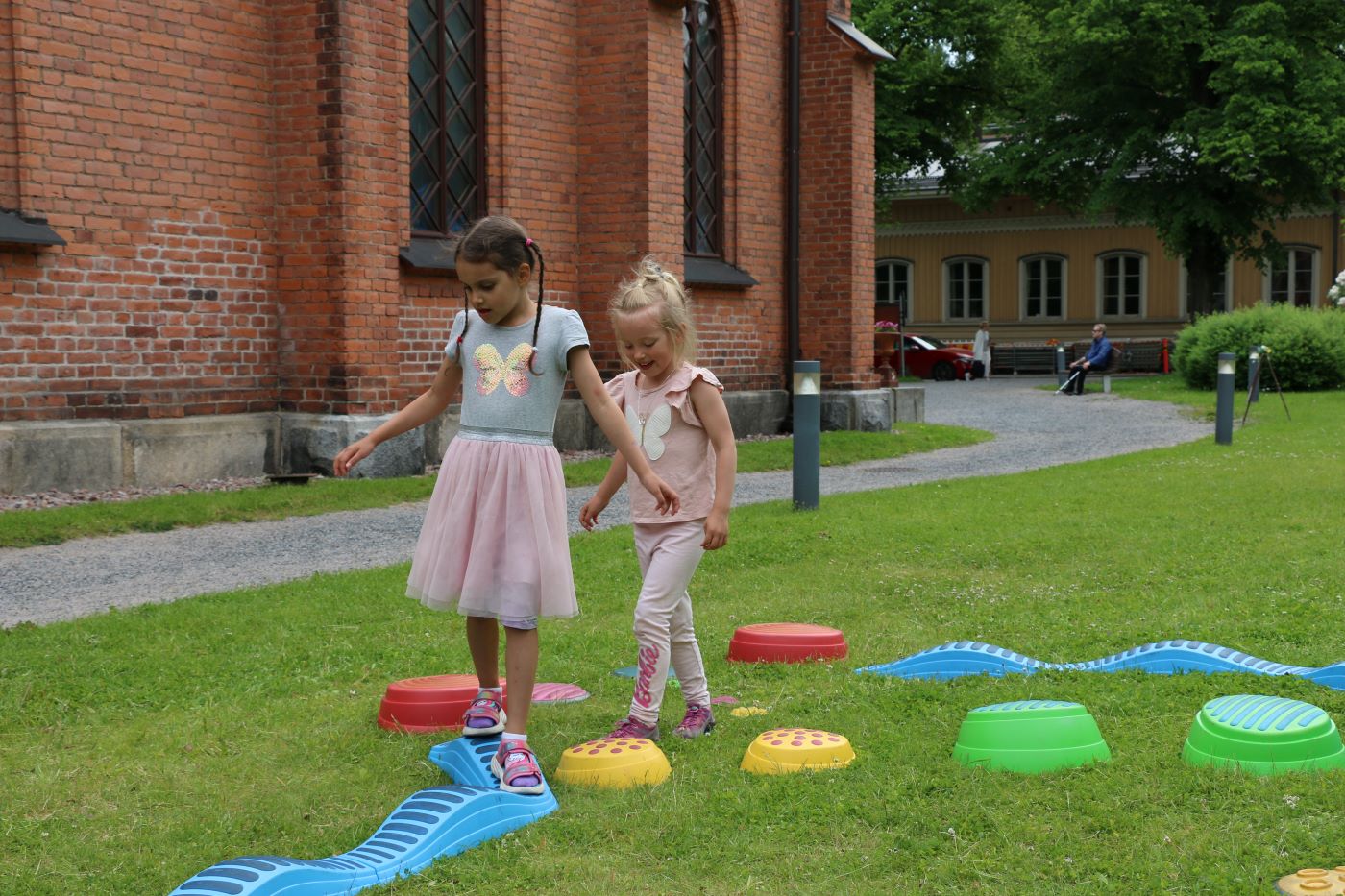 Sela Aleman (vas.) ja Matilda Paloaho leikkivät lasten kesäpihalla Finlaysonin kirkolla.