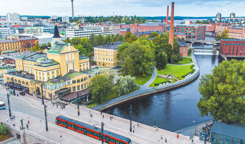 Kesäinen ilmakuvan Finlaysonin katolta Tammerkoskelle etelän suuntaan, jossa Tammerkoskea ympäräivät punatiiliset rakennukset.