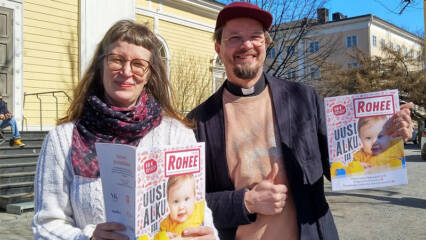 Hannele Huhtala ja Olli Viljakainen Vanhan kirkon edustalla pitävät käsissään Rohee-lehtiä.