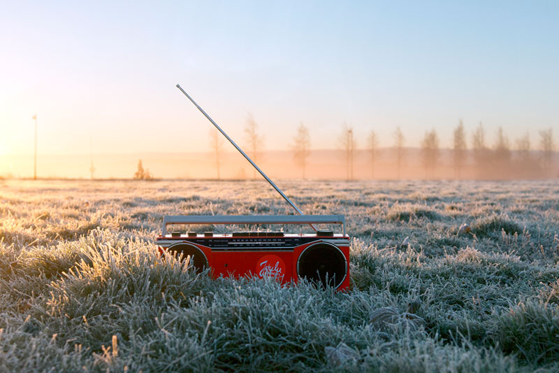 Punainen radiomankka maassa huuruisella pellolla, ja taustalla puiden välistsä laskee aurinko.