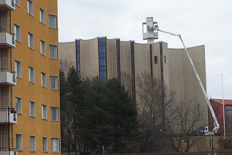 Nostokurki ulottuu kirkon katolla olevalle ristille ja vasemmalla on kerrostalo.