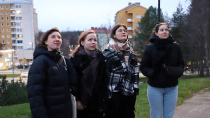 Neljä nuorta naista seisoo vierekkäin lämpimästi pukeutuneena ulkona.
