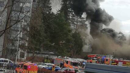 Etualalla ploautoja ja takana keroostalojen välissä näkyy tummaa savua, joka peittää maiseman.