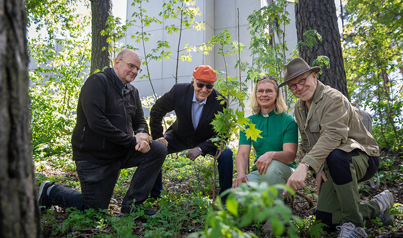 Neljä ihmistä nojaa polveensa metsikön reunassa Pispalan kirkon vieressä.